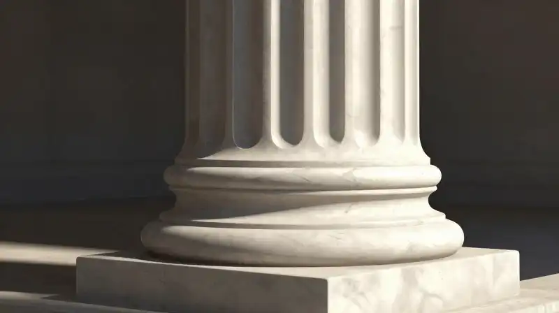A smooth marble column is dramatically highlighted by sharp sunlight
